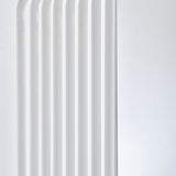 Close-up of the Echo White Free Standing Mirror's edge, showing stacked white powder-coated metal slats with gaps and a curved base against a plain light background.