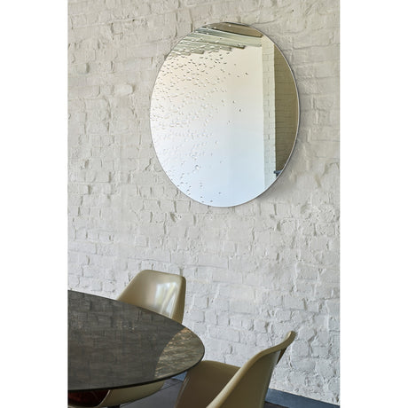 Matin frameless round wall mirror, 100cm, with hand-applied dewdrop texture across the glass, shown above a dining table in a whitewashed brick room.