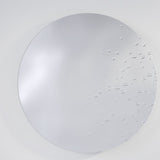 Matin Hand Applied Dewdrop Round Wall Mirror 60cm, a frameless round glass mirror with raised dewdrop details clustered across the lower right edge, shown against a plain light grey background.
