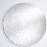 The dewdrop mirror seen larger, the drops gathered more thickly to one side and thinning across the face.