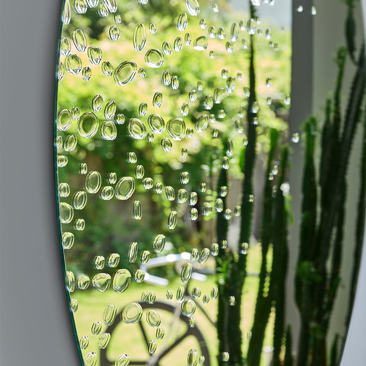 Close-up of the drops with a garden reflected through them, each one bending the greenery behind it.