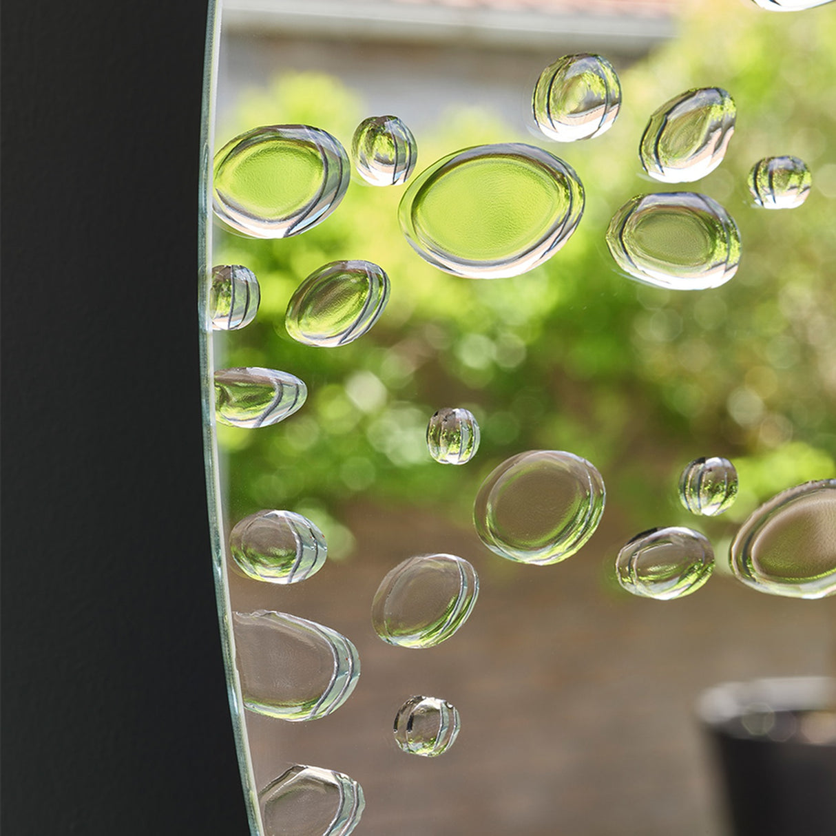 Close-up of the drops against reflected foliage, reading as small lenses rather than as surface texture.