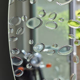 Close-up of the drops reflecting a garden, with the plain silvered glass showing clear between each one.
