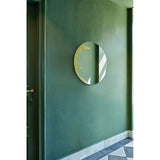 Ornato Gold Leaf Round Rotating Wall Mirror 70cm, frameless round glass with hand-applied gold leaf patch on one edge, mounted on a green wall in a hallway setting.