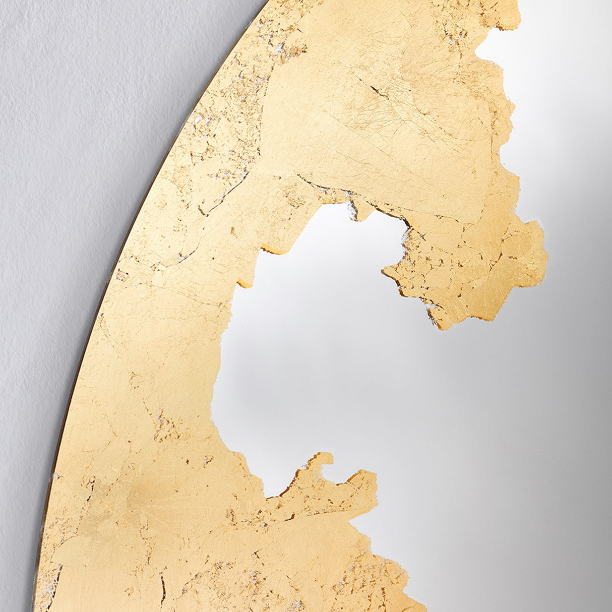 Close-up of the Ornato Gold Leaf Round Rotating Wall Mirror 70cm, showing hand-applied gold leaf with a torn, irregular edge against the plain mirror surface.