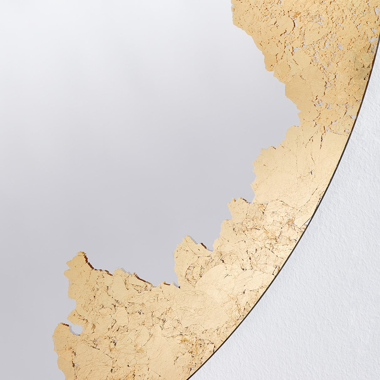 Close-up of the gilding meeting the plain glass, the leaf thinning to broken flecks along the join.