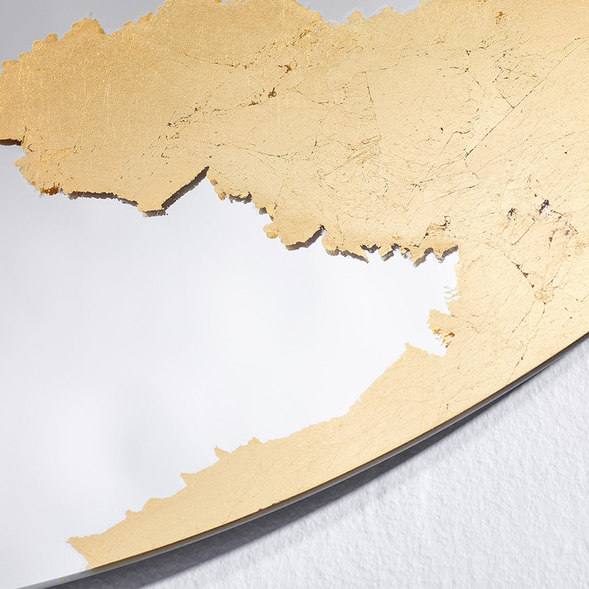 Close-up of the gold leaf surface, the crazing and overlaps of the individual sheets visible across it.