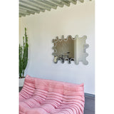 Wiggle Scalloped Edge Wall Mirror 133cm with a wavy, frameless outline and engraved inner border, hung above a pink sofa in a living room setting.