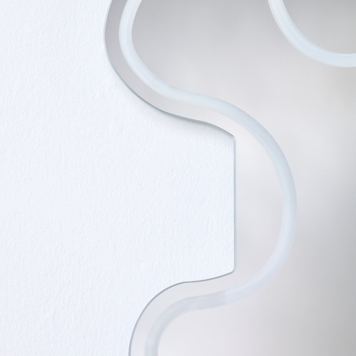 Close-up of the Wiggle Scalloped Edge Wall Mirror 133cm, showing the frameless glass edge with its wavy outline and engraved border line against a plain white wall.