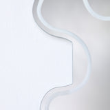 Close-up of the Wiggle Scalloped Edge Wall Mirror 133cm, showing the frameless glass edge with its wavy outline and engraved border line against a plain white wall.