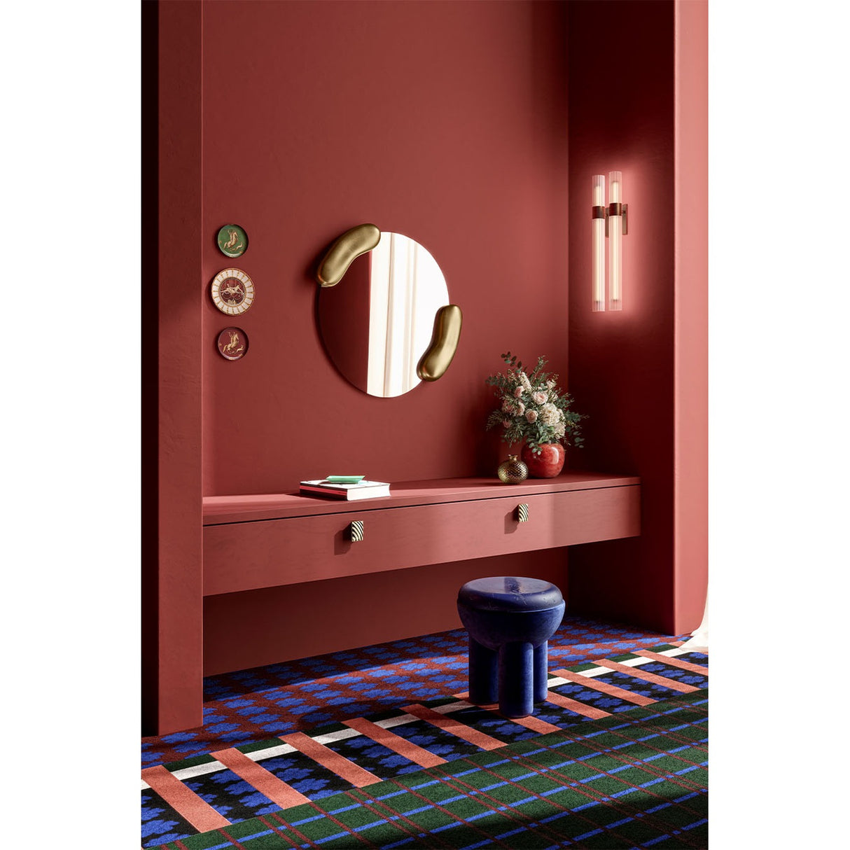 Calco Gold Leaf Sculpted Round Wall Mirror, 73cm, with organic gold-leaf forms at each side, shown above a red console table in a red-toned hallway setting.