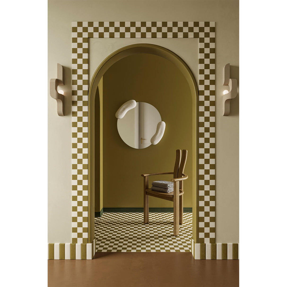 Calco White Sculpted Round Wall Mirror, 73cm, with organic white moulded forms at each side, shown in an arched hallway above a wooden chair.
