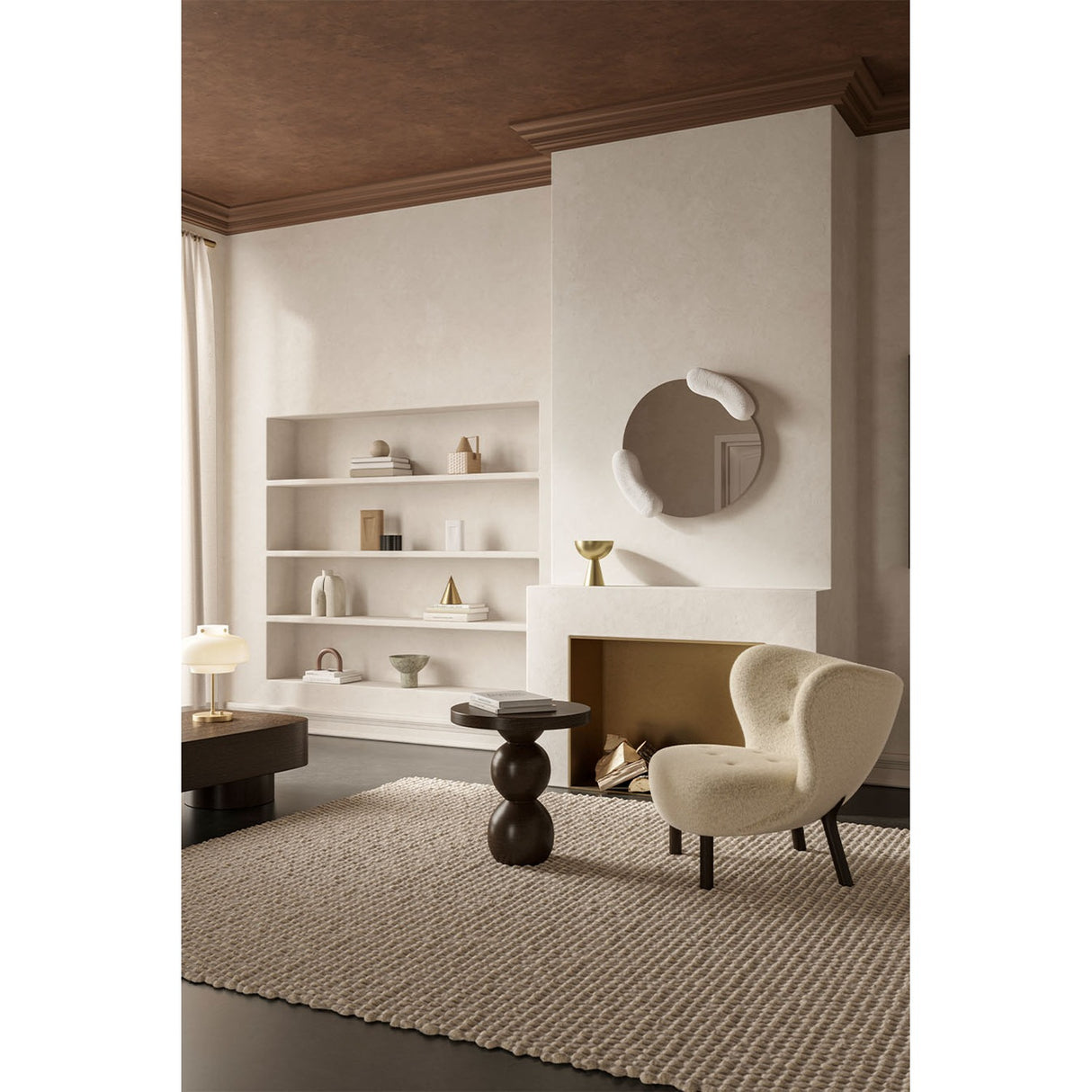 Calco White Sculpted Round Wall Mirror 73cm mounted above a fireplace, with two white moulded forms holding the asymmetric glass, in a neutral living room setting.