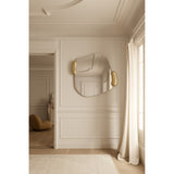 Calco Gold Leaf Sculpted Wall Mirror 116cm with irregular frameless glass and gold leaf sculpted side accents, shown mounted in a hallway with panelled walls.