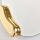 Calco Gold Round wall mirror, close-up of a sculpted gold leaf form appearing to hold the asymmetric mirror glass, set against a plain white background.