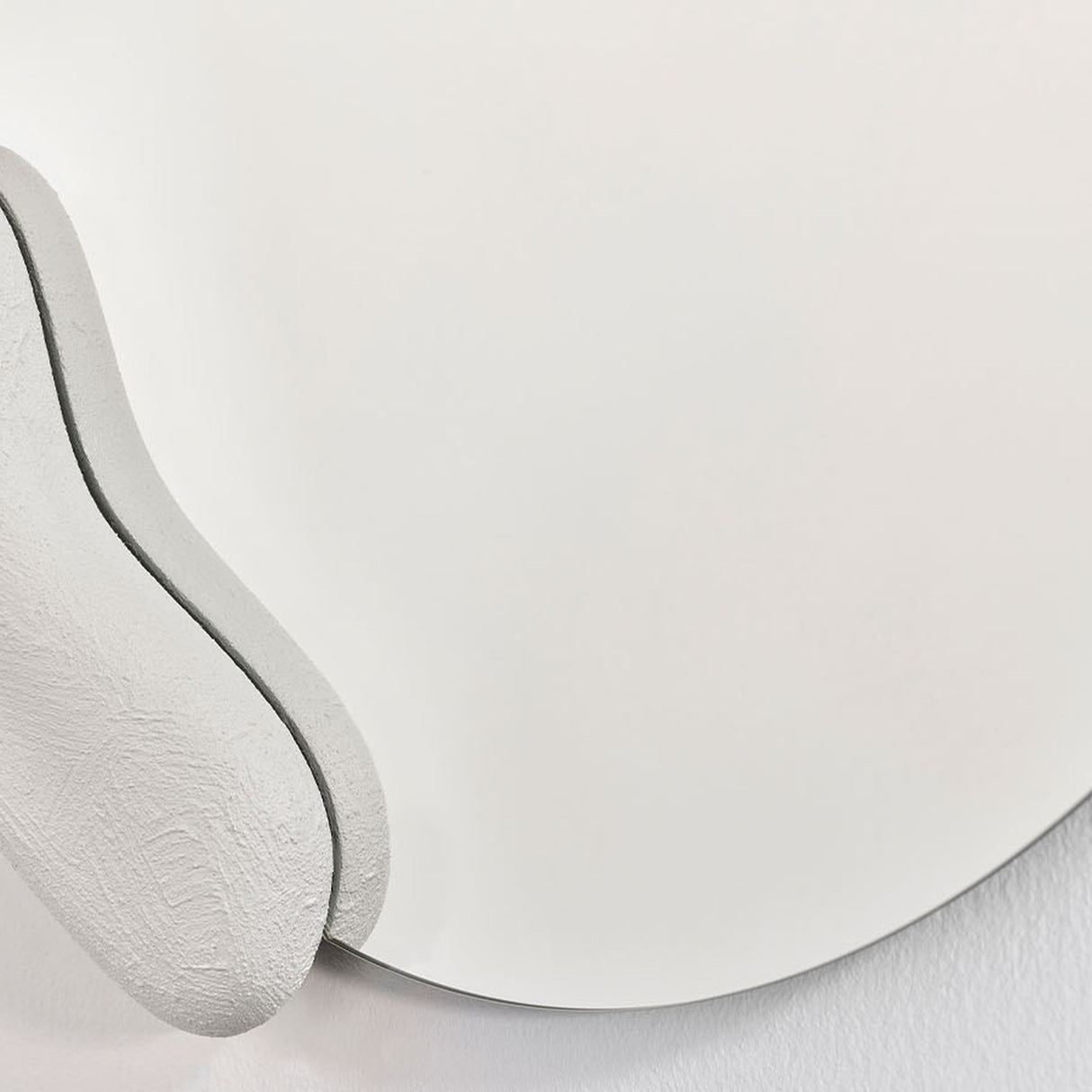 Calco White Sculpted Round Wall Mirror 73cm, close-up of the organic frameless glass edge with a white sculpted composite form and visible brush texture.