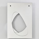 Infinito Precision Cut Void Wall Mirror 100cm, a white rectangular panel with an organic cut-out void outlined in a thin black line, mounted with two visible fixing points on a plain grey background.