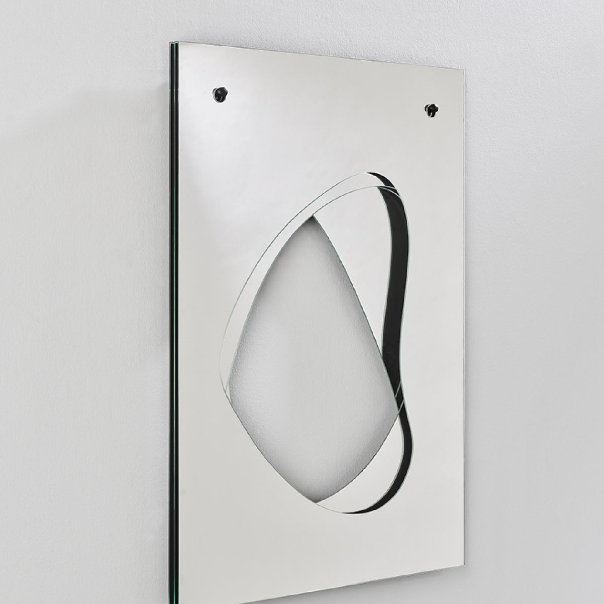 Infinito Precision Cut Void Wall Mirror 100cm, a rectangular white panel with an organic cut-out void revealing layered mirrors set behind the surface, shown at an angle against a plain wall.