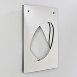 Infinito Precision Cut Void Wall Mirror 100cm shown at an angle, a rectangular white panel with an organic cut-out void revealing layered mirror glass beneath, against a plain light background.
