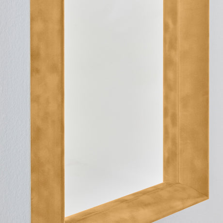 Close-up of the Velvet Ochre rectangular wall mirror's corner, showing the deep ochre velvet box frame with recessed glass and a light grey wall background.
