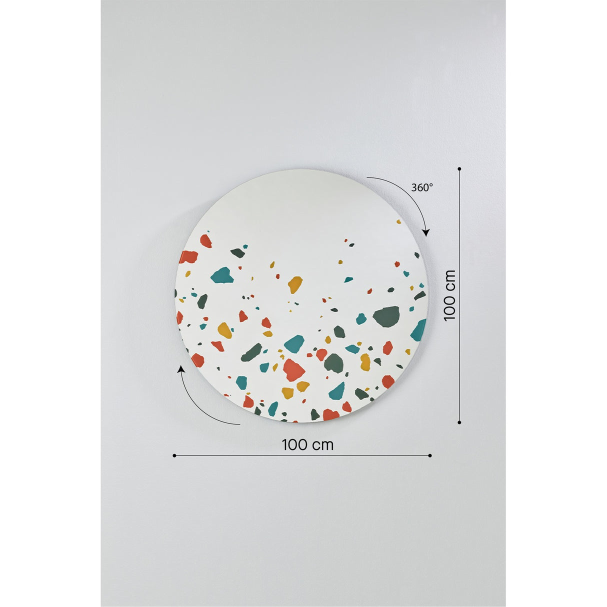 Round frameless wall mirror, 100cm diameter, with terrazzo-effect chips in red, teal, ochre and grey clustered along the lower edge, shown with dimension markers on a plain grey background.