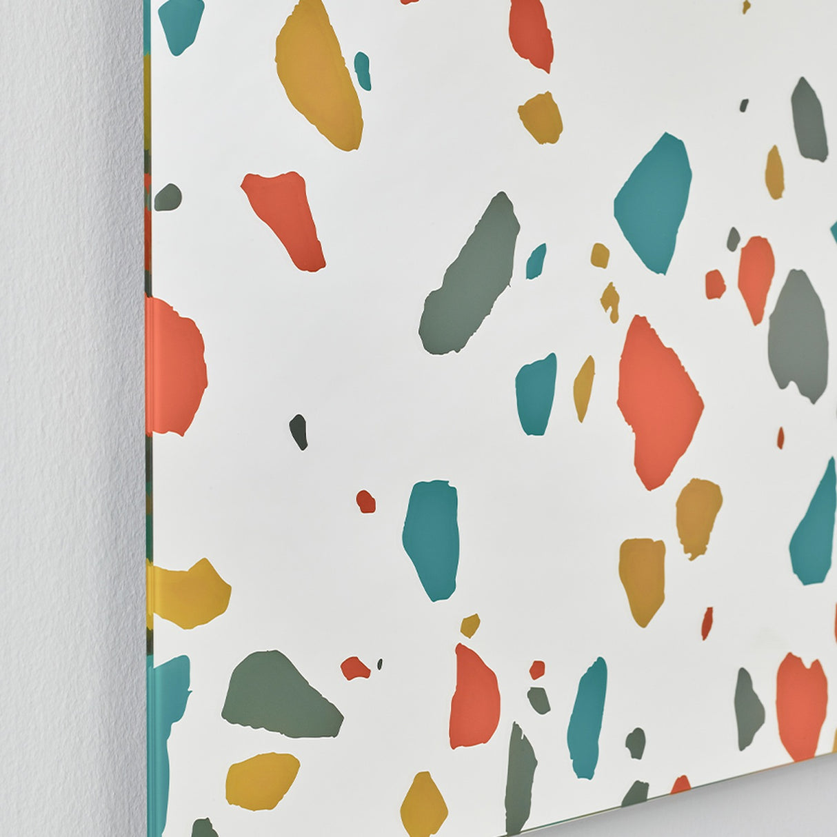 Terrazzo Rectangular Printed Glass Wall Mirror 120cm, frameless rectangular mirror with red, teal, ochre and grey terrazzo chips printed on the silvered glass edge, shown against a plain white wall.