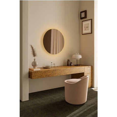 Brio Bronze round wall mirror with warm white LED backlighting, frameless bronze mirrored glass, mounted above a wood dressing table in a living space.