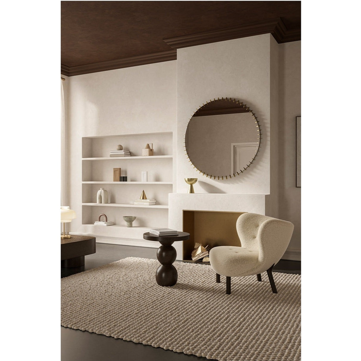 Ray Powder Coated Round Wall Mirror 105cm in gold, framed by small interlocking discs, hung above a fireplace in a living room with shelving and an armchair.