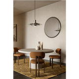 Ray Black Powder Coated Round Mirror with radiating metal spoke frame, reflecting a pendant light, hung above a dining table in a neutral-toned room.