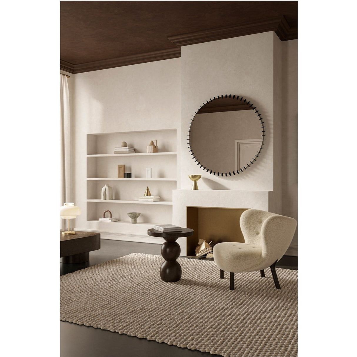 Ray Black round wall mirror with a black powder coated metal frame and radiating spoke detail, hung above a fireplace in a neutral living room setting.
