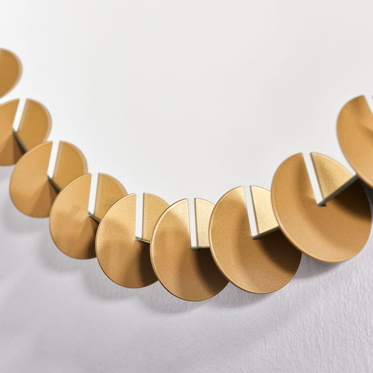 Close-up of the Ray Gold Disc Edged Round Wall Mirror 65cm, showing interlocking gold metal discs arranged around the mirror's edge against a plain white background.