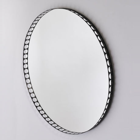 Round wall mirror with a black metal rim perforated by a row of round cut-out holes, shown at an angle against a plain light grey background.