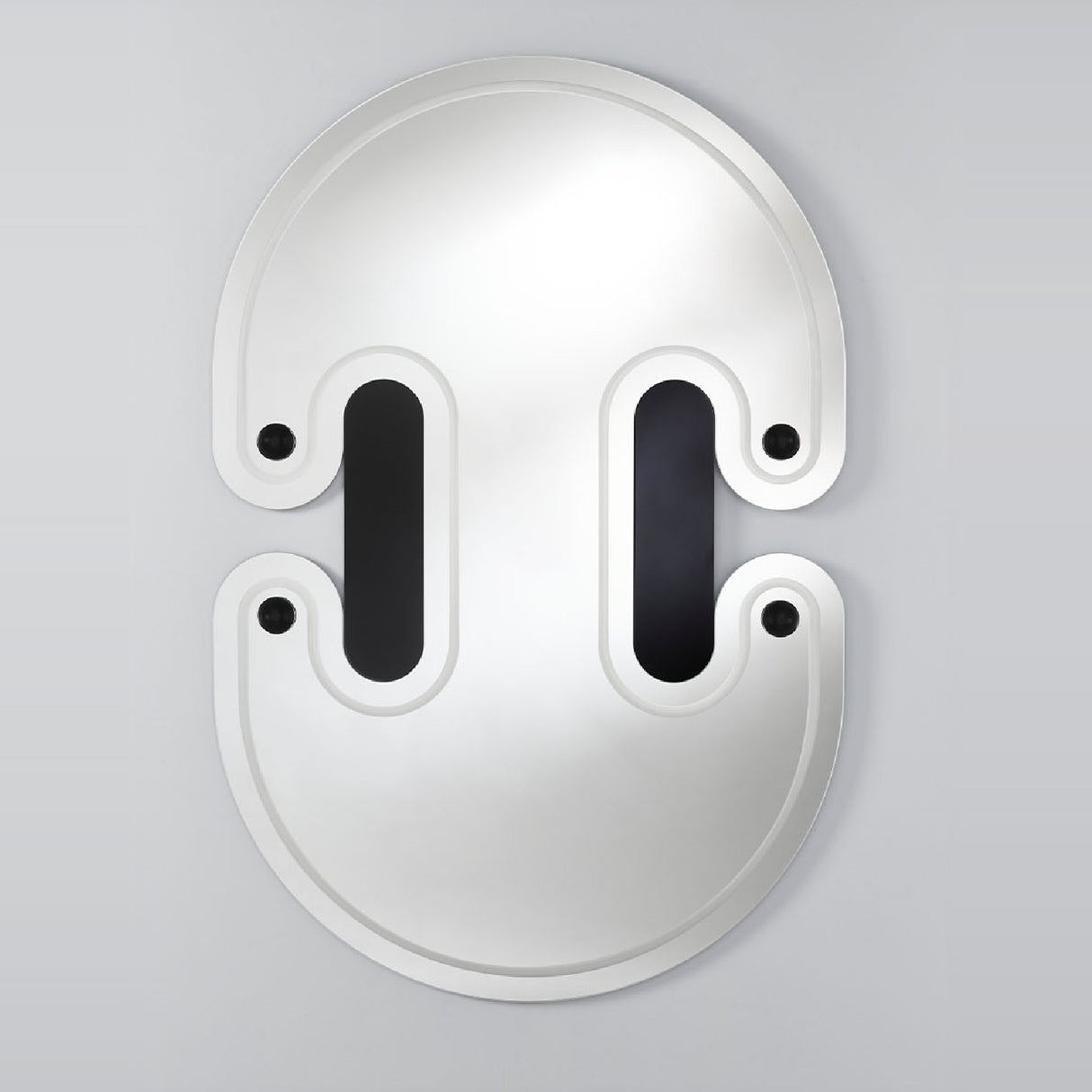 The mirror seen larger, the twin lobed outline with the engraved slots and spheres set across the face.