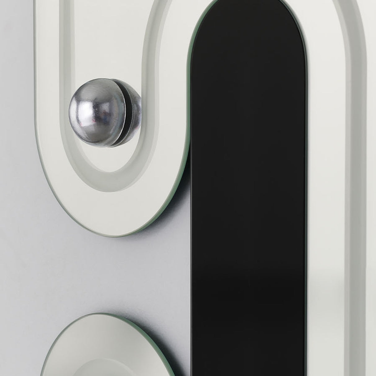 Close-up of the Satellite Silver Leaf Engraved Orbit Wall Mirror, showing a chrome half-sphere and black lacquered glass ellipse set into the silvered, curved frame.