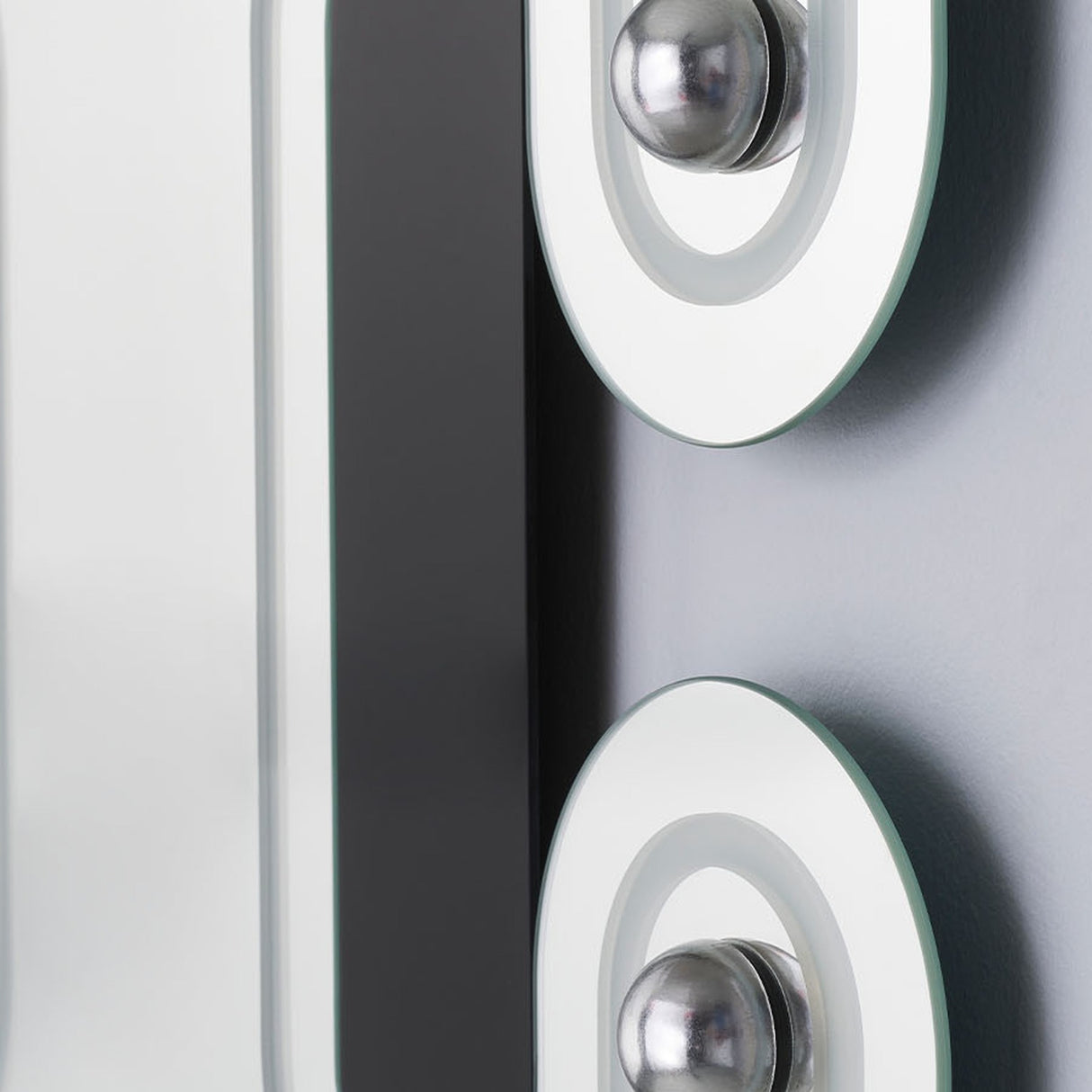 Close-up of the Satellite Silver Leaf Engraved Orbit Wall Mirror, showing mirrored glass with a black lacquered ellipse and silver metal leaf half-sphere details.