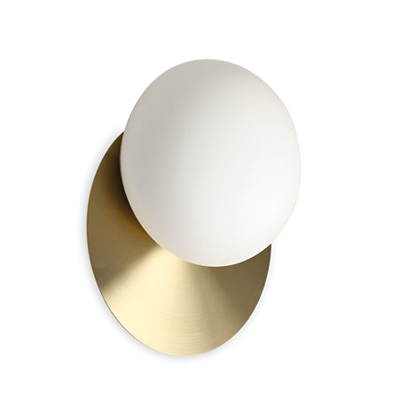 The Halion Wall Light - Brass is a wall-mounted fixture with a large, white spherical bulb set on a circular brass base. Its elegant design and brushed finish offer modern sophistication to any space.