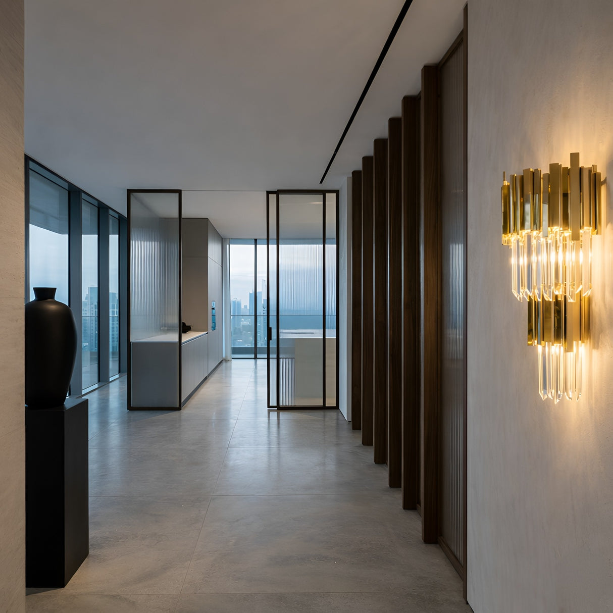 A modern, minimalist hallway with large windows, light gray floors, a black vase on a pedestal, vertical wooden slats, and the Royal Crystal Wall Light - Gold illuminating the space, overlooking a stunning city skyline.