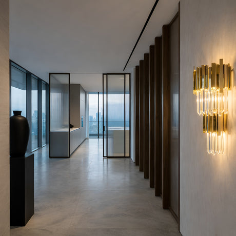 A modern, minimalist hallway with large windows, light gray floors, a black vase on a pedestal, vertical wooden slats, and the Royal Crystal Wall Light - Gold illuminating the space, overlooking a stunning city skyline.