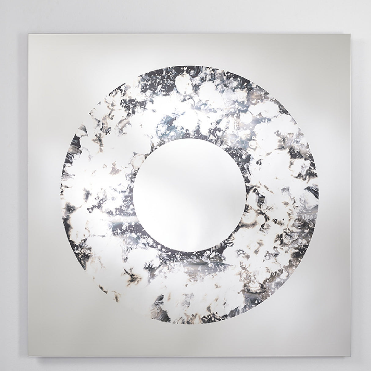 The square mirror turned slightly, the poured ring standing out against the flat industrial silvering behind it.