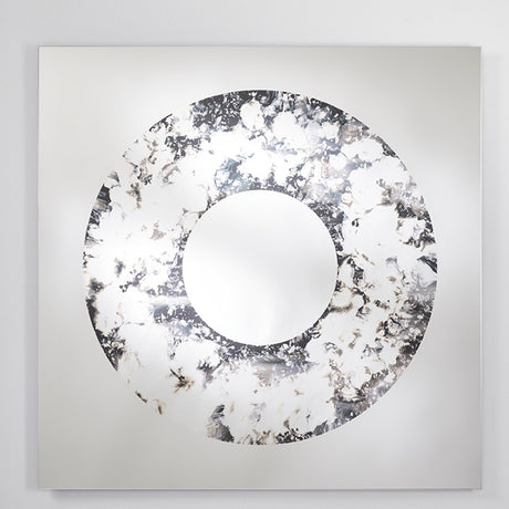 The square mirror turned slightly, the poured ring standing out against the flat industrial silvering behind it.