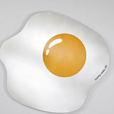 The egg shaped mirror seen at a shallow angle, the printed yolk and its single highlight catching the light.
