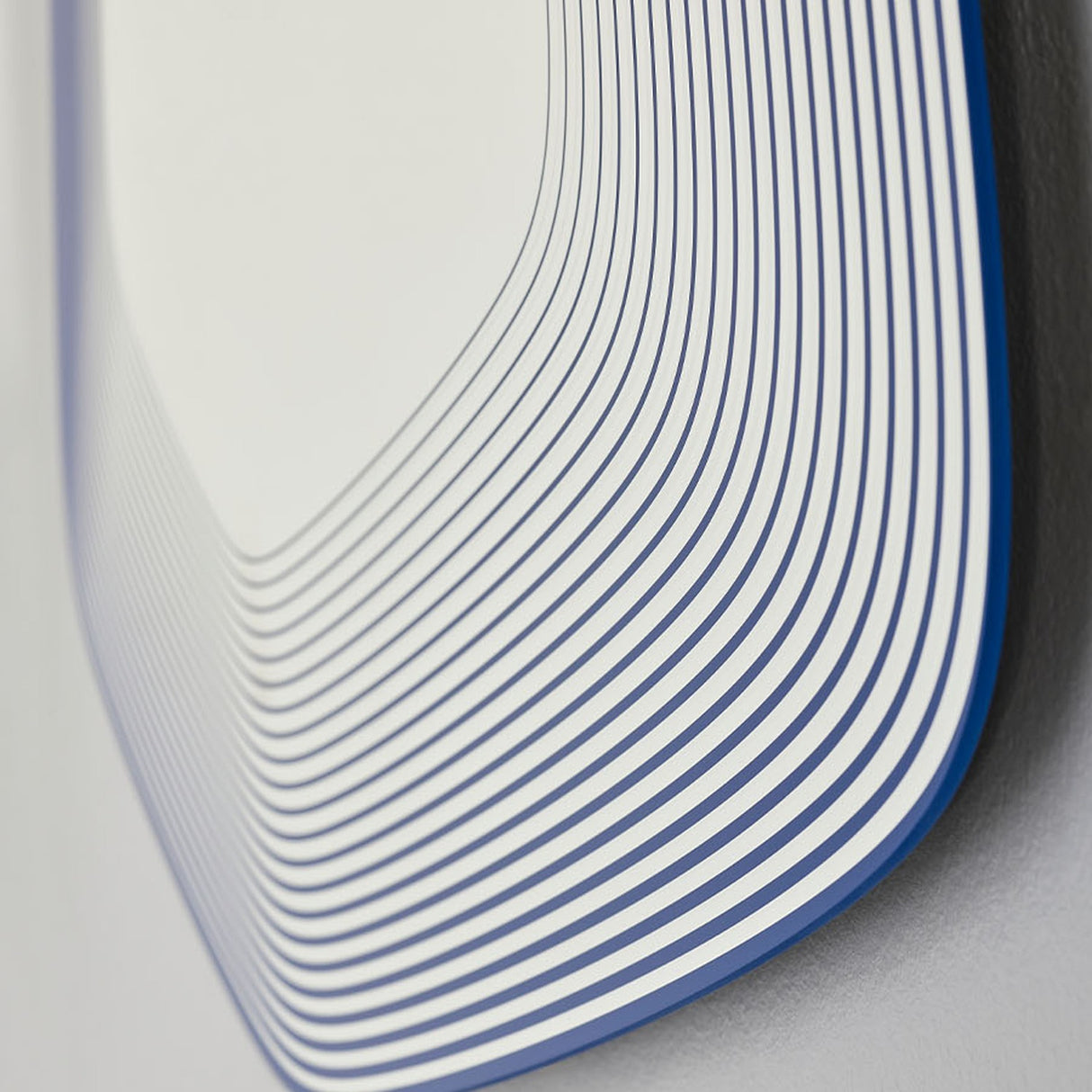 Close-up of the Vibe Blue Line Print Irregular Wall Mirror 80cm, showing concentric blue lines on glass forming a soft five-sided frameless shape.