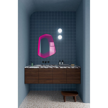 Vibe Pink Line Print Irregular Wall Mirror 80cm, an irregular frameless mirror with concentric magenta line detailing, shown above a dark wood vanity in a bathroom setting.