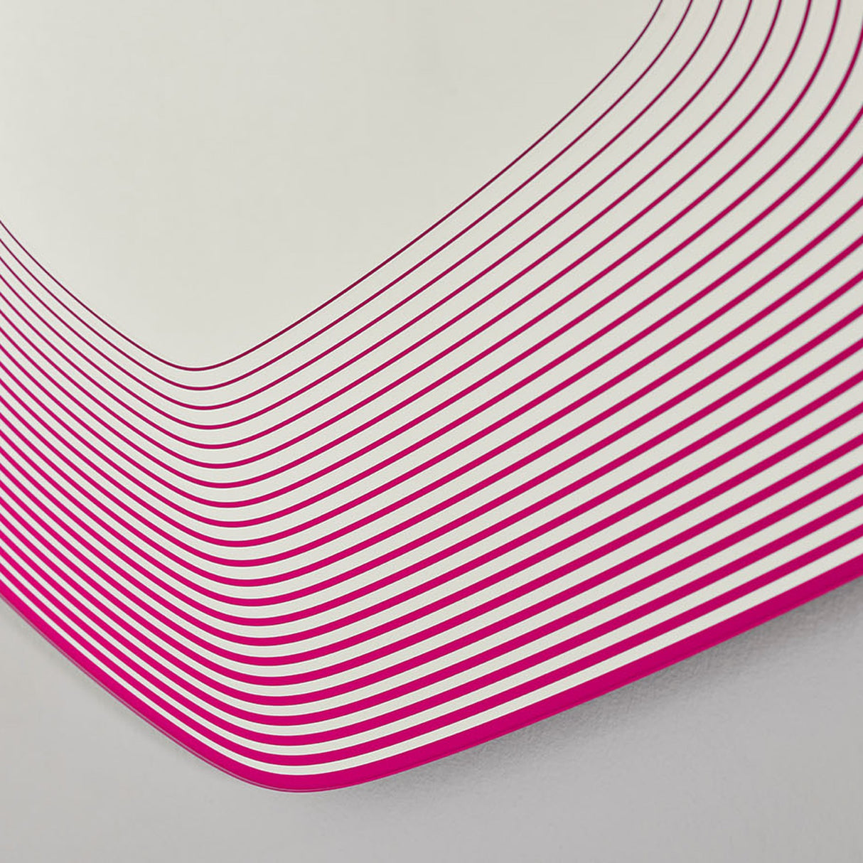 Close-up of the Vibe Pink Line Print Irregular Wall Mirror, showing concentric magenta lines curving on frameless glass against a plain light background.