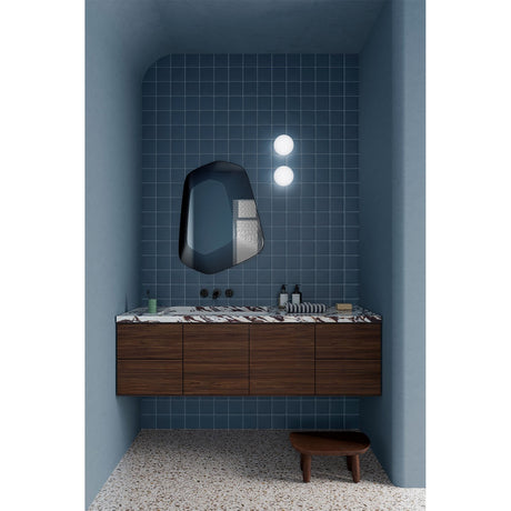 Vibe Black Line Print Irregular Wall Mirror 80cm with concentric black line detailing, mounted above a walnut vanity in a blue-tiled bathroom.