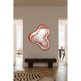 Nimbus Orange Banded Glass Wall Mirror 123cm with an irregular, cloud-like outline in orange and silvered bands, shown mounted above a dark bench in a hallway.