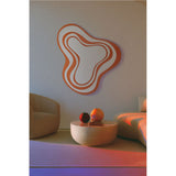 Nimbus Orange Banded Glass Wall Mirror 123cm, an irregular cloud-shaped mirror with concentric orange and mirrored bands, shown mounted above a sofa and round coffee table in a living room.