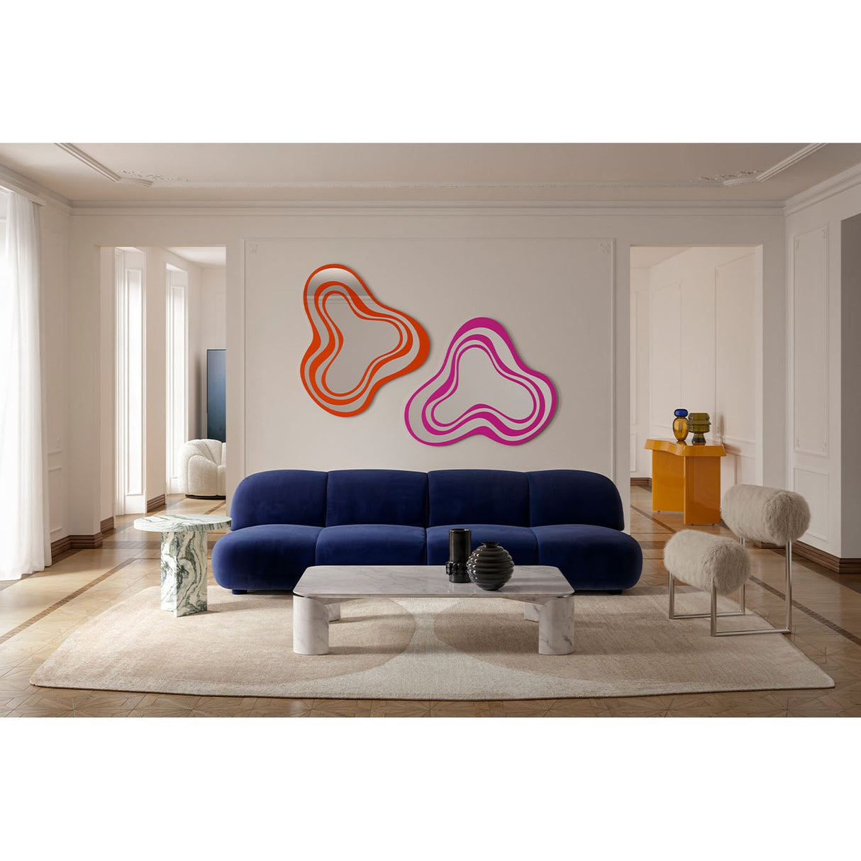 Nimbus Pink Banded Glass Wall Mirror 123cm shown alongside an orange version above a navy sofa, its irregular cloud-like outline formed by concentric pink and mirrored bands.