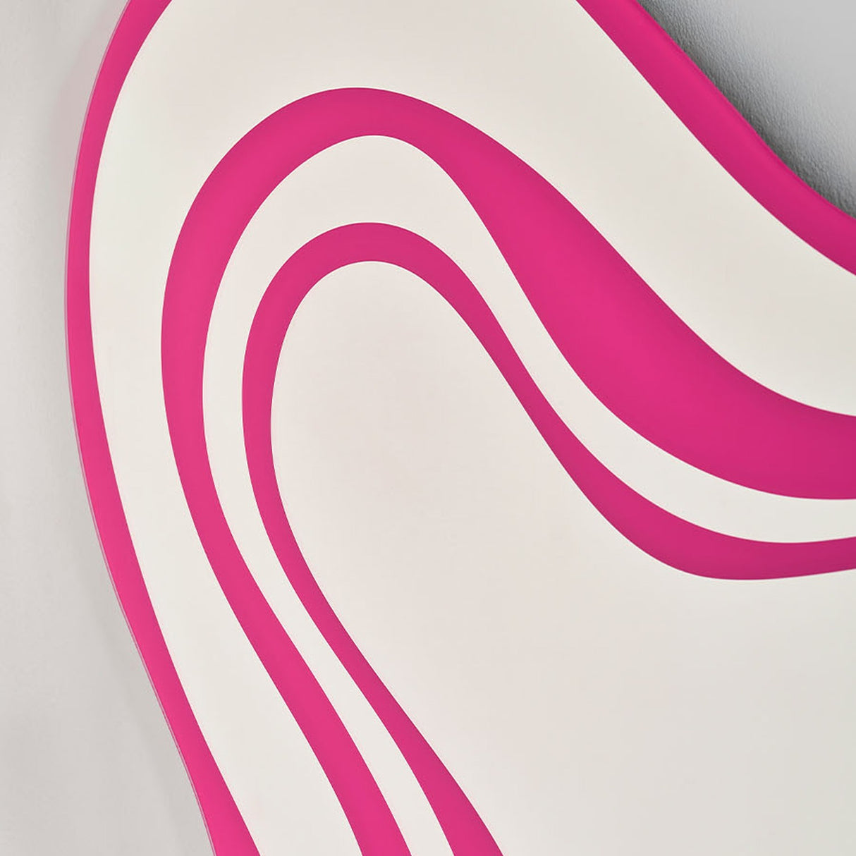 Close-up of the Nimbus Pink Banded Glass Wall Mirror, showing frameless irregular curves in alternating pink and mirrored glass bands against a plain light background.