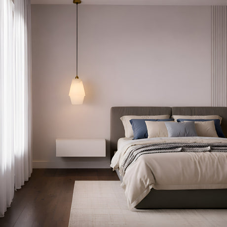 Minimalist bedroom with a neatly made bed featuring beige and blue pillows, a soft beige comforter, the Bellorin 1 Light Large Alabaster Single Pendant Light in Soft White & Brushed Brass, sheer white curtains, and dark wood flooring.
